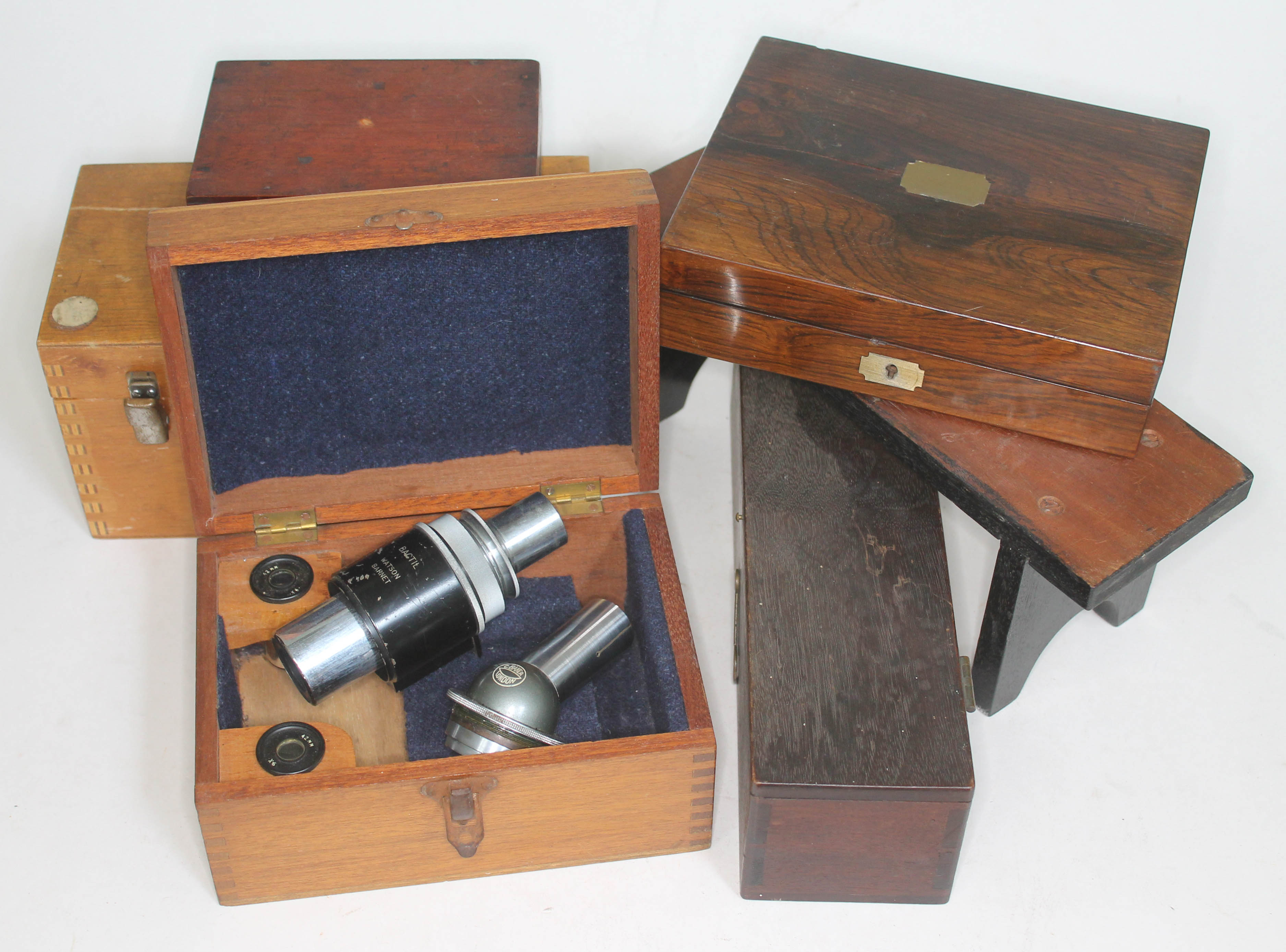 Two microscope lenses together with various empty instrument boxes.