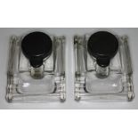 A pair of moulded glass ink wells with bakelite tops length 13cm.