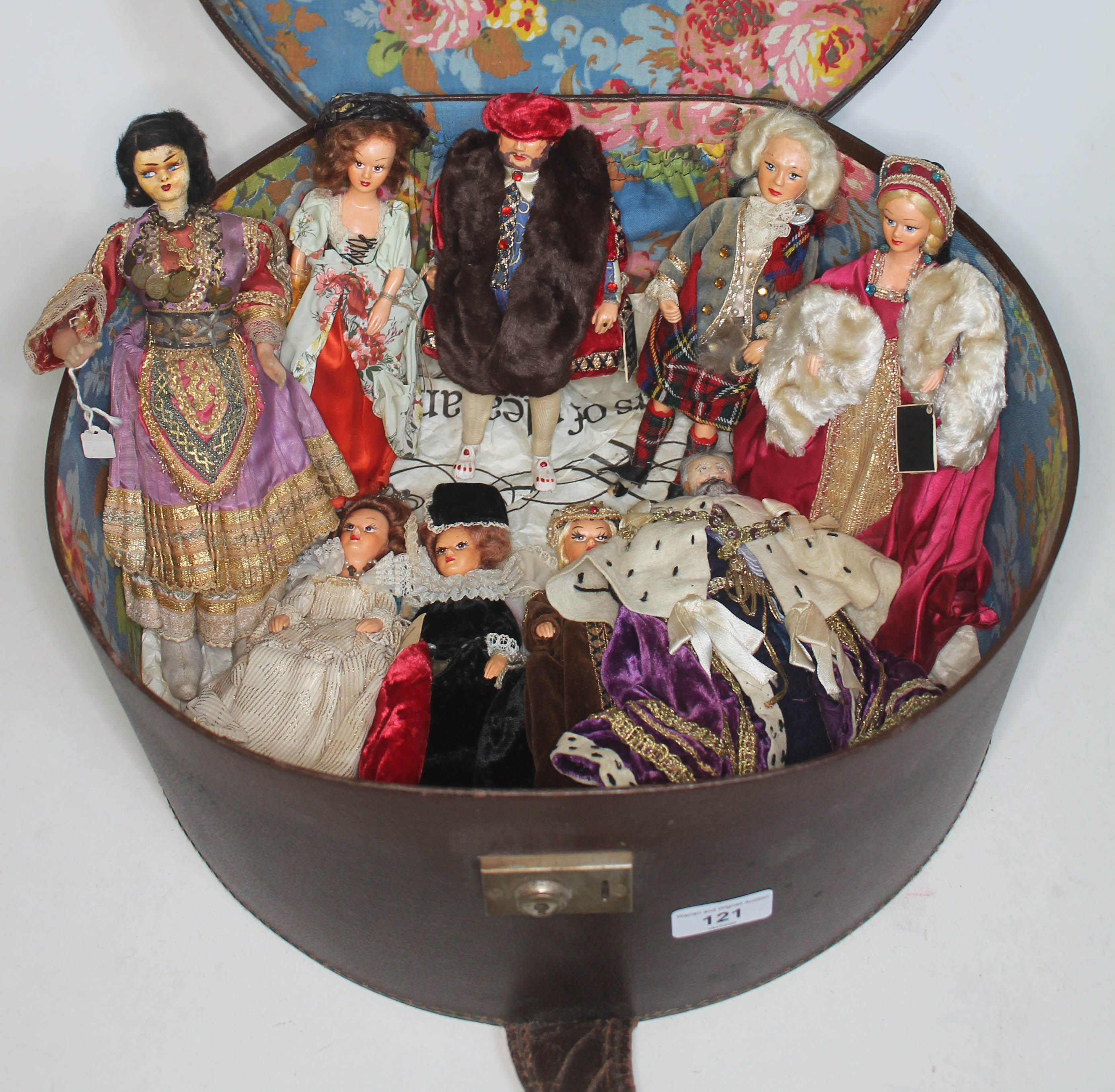 A vintage circular hat box containing various Peggy Nisbet dolls including Henry VIII and various