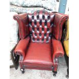 An oxblood leather chesterfield wing back armchair