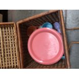 A wicker picnic basket complete with plastic cutlery, plates and mugs.