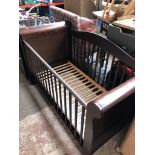 A dark wood toddler cot bed