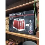 A boxed Russell Hobbs Inspire red 2 slice toaster.