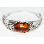 A Polish bangle of open floral design and set with an amber cabochon, marked '925' and Poland',