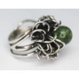 A contemporary white metal ring with random wire setting supporting a jadeite bead, band unmarked,