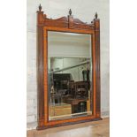A George III style mahogany mirror having turned urn finials, scrolls interspersed by classical