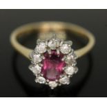 A cluster ring set with a central oval cut pinkish purple almandine garnet and surrounded by ten