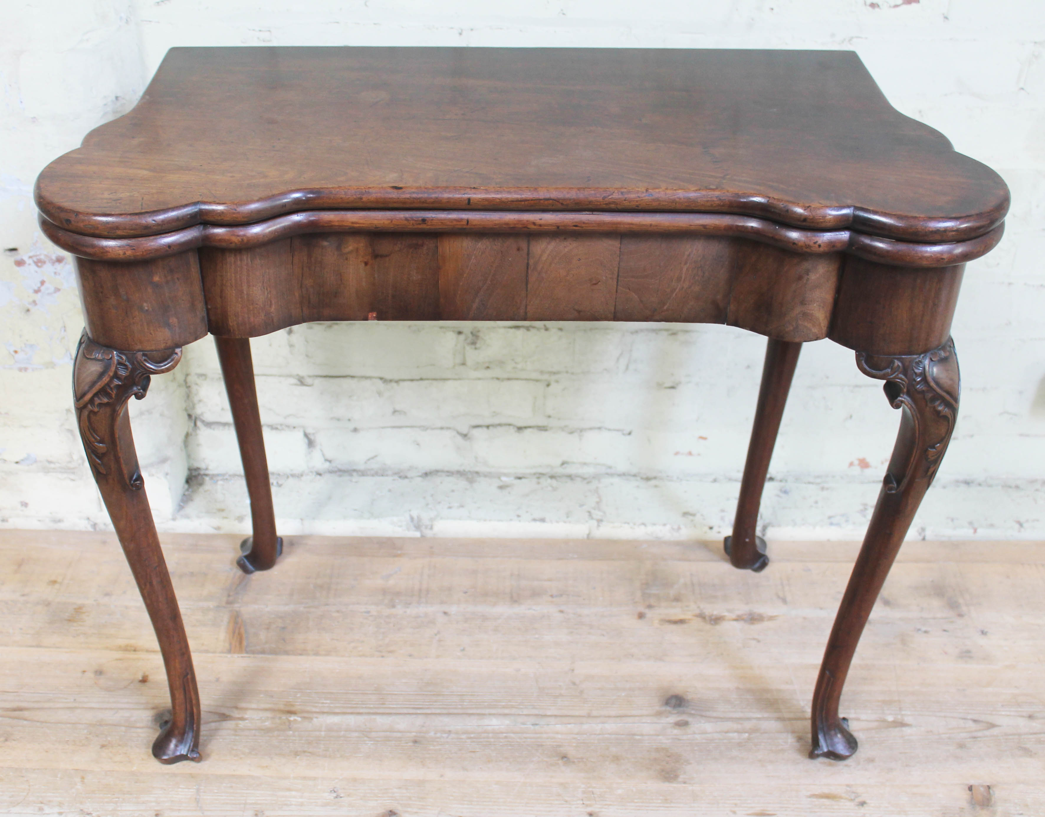 A George II mahogany games table, circa 1740, with fold-over top, the green baize lined interior