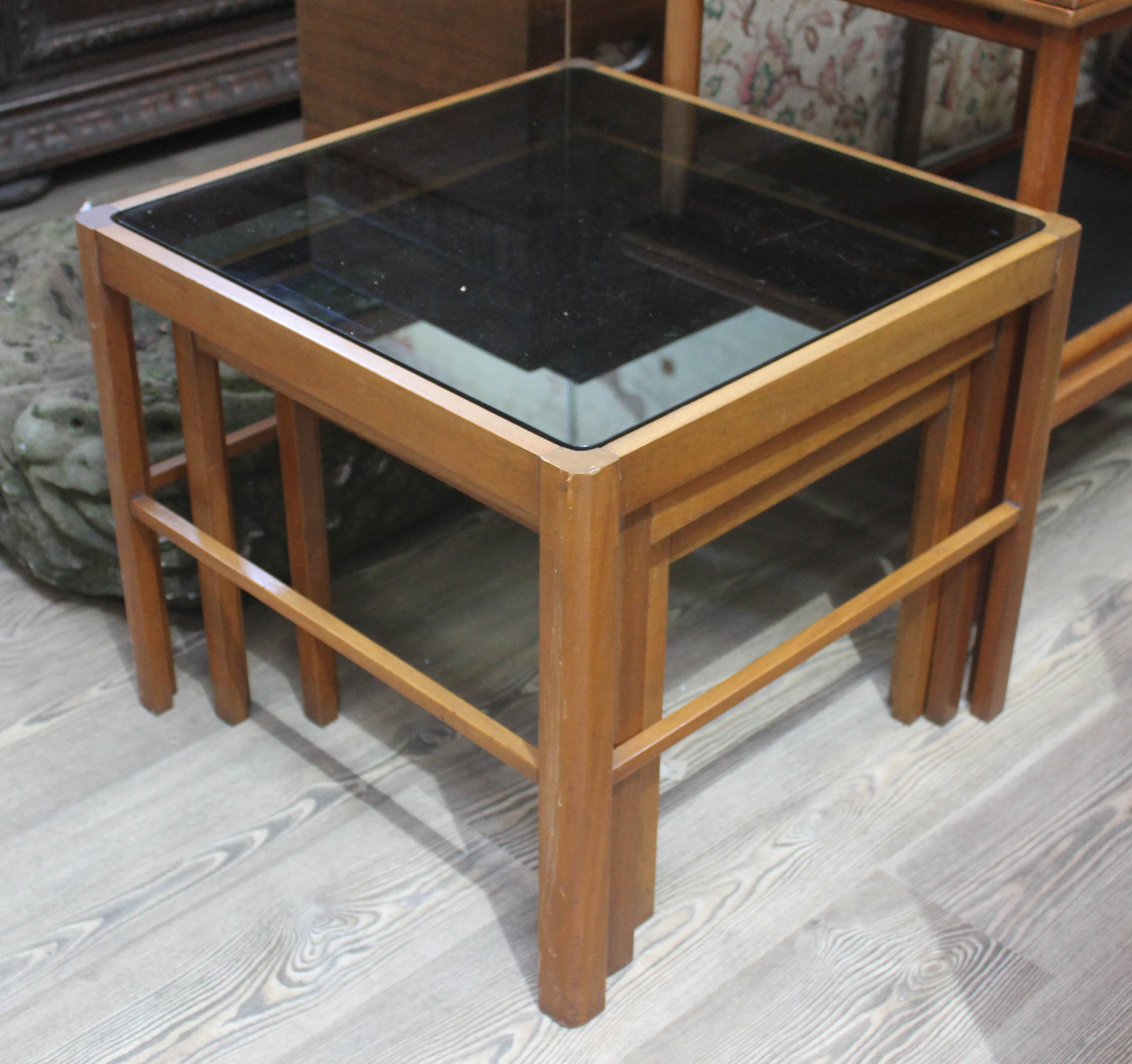 A retro teak nest of tables with smoked glass tops.