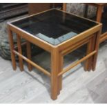 A retro teak nest of tables with smoked glass tops.