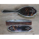 A three piece hallmarked silver and tortoiseshell dressing table set comprising two brushes and a