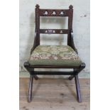 An ecclesiastical oak chair with X frame and pierced back.