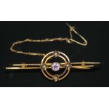An Edwardian bar brooch set with a central facetted amethyst within two concentric circles set