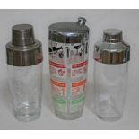 Three glass cocktail shakers with aluminium tops, one plain, one marked with measures, and one
