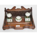 A late Victorian/early Edwardian carved oak standish with a pair of ceramic inkwells and bowl.