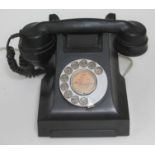 A vintage black bakelite telephone.