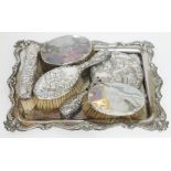 A silver plated tray containing hallmarked silver backed brushes and hand mirror.