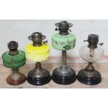 A group of four Victorian brass pedestal oil lamps with glass reservoirs, three with pot bases and