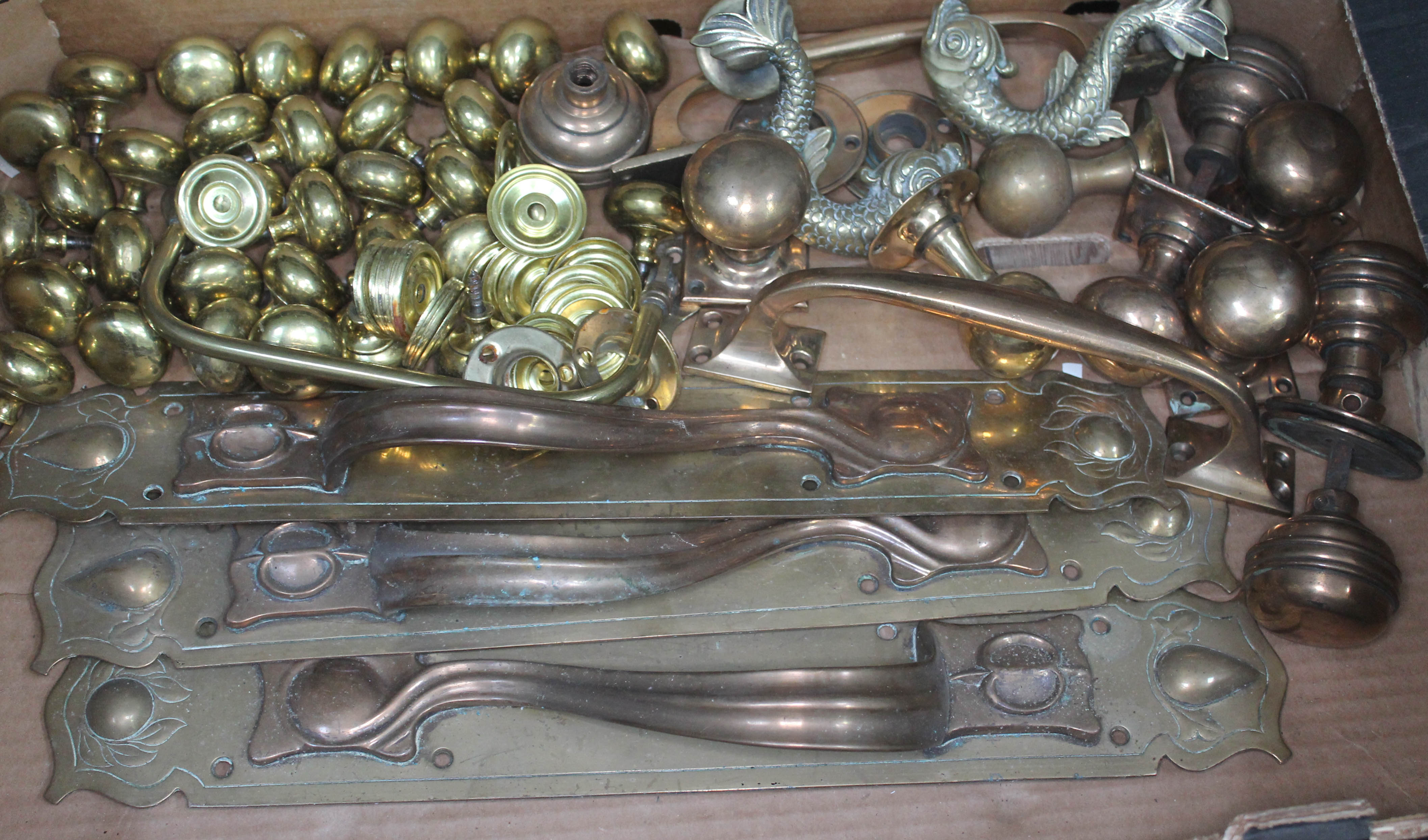 A box of brass door fittings including Art Nouveau style handles etc.