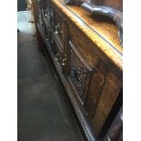 An oak sideboard with carved panels, rail back and twist legs