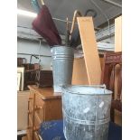 A galvanised bucket and another bucket containing umbrellas