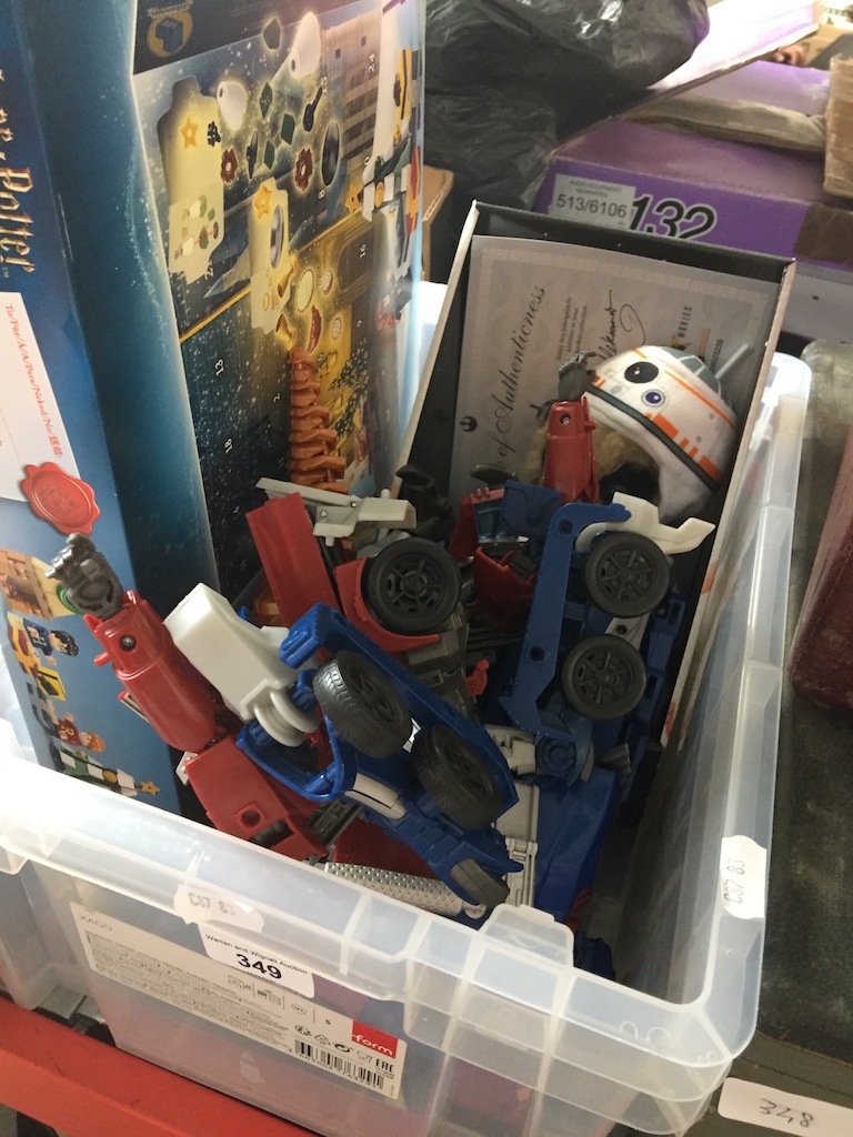 A crate of toys including Lego Harry Potter set, transformer style toys and Star wars meerkat toy