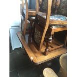 An oak drawer leaf table with carved bulbous legs and feet together with four chairs having floral