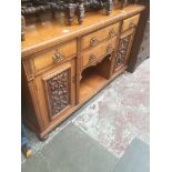 An Edwardian large oak sideboard with carved door panels, lower pot board and bun feet