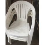 Four white plastic stacking chairs