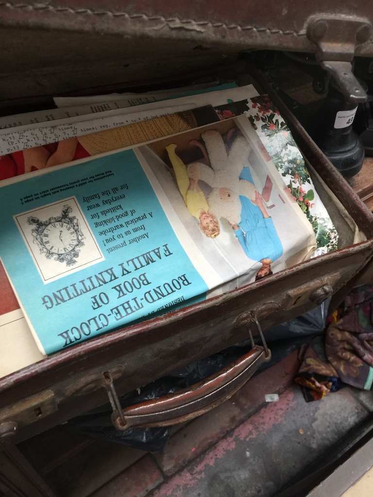 A vintage suitcase containing sewing patterns etc