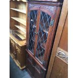 An oak corner display cabinet with leaded glass windows