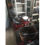 A red single front wheel mobility scooter with charger and keys.