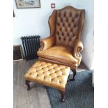 A mustard Chesterfield button and wing back armchair with matching foot stool.