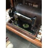A vintage Singer hand cranked sewing machine with case