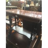 A mahogany two tier console table with ceramic castors