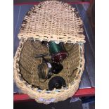 A small fishing basket containing 2 fishing reels to include Moris Shakespeare.