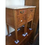 A pair of continental oak bedside cabinets with veined marble tops, carved floral decoration on