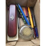 A box containing antique brass top inkwelland various pens including green marble Conway Stewart
