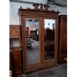 A French 19th century oak wardrobe with double full length mirrored doors, carved and finial cornice