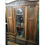 A Continental oak mirror door wardrobe circa 1900 with carved floral decoration and three lower