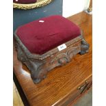 A 19th century carved oak foot stool with carved animal faces and upholstered and hinged top