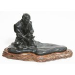 A Japanese bronze okimono depicting a man seated preparing food, signed, on carved wood base, length