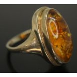 A hallmarked 9ct gold ring set with an oval amber cabochon, measuring approx. 19mm x 9mm x 5mm.