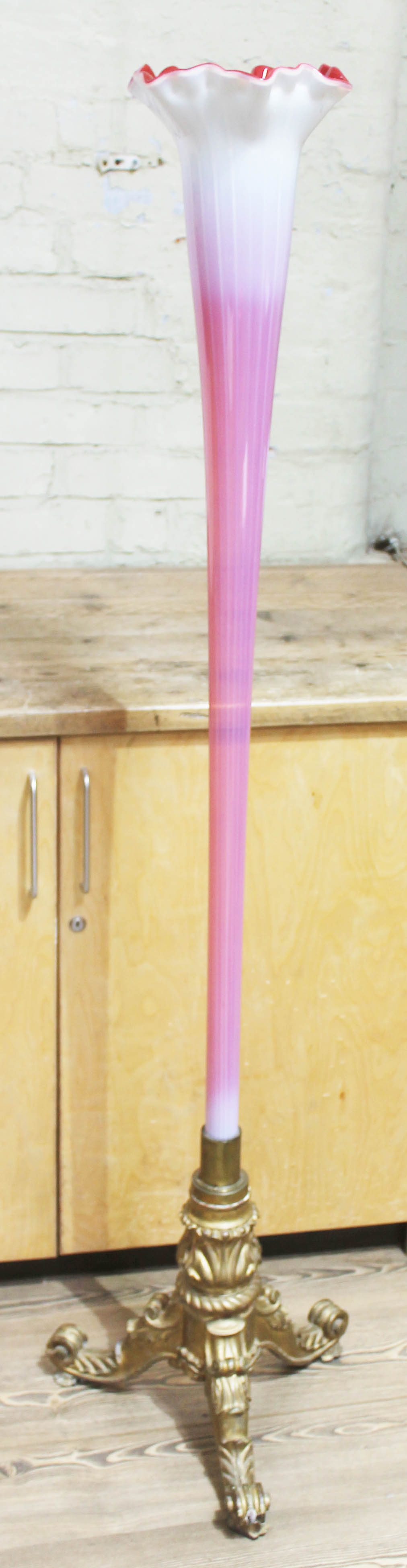 A large floor standing cranberry and vasoline glass trumpet vase with crimped rim, joined to a gesso