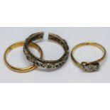 A group of three rings comprising an indistinctly marked wedding band, a three stone ring marked '