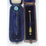 Two stick pins, one set with a cluster of turquoise cabochons and the other a yellow metal sphere,