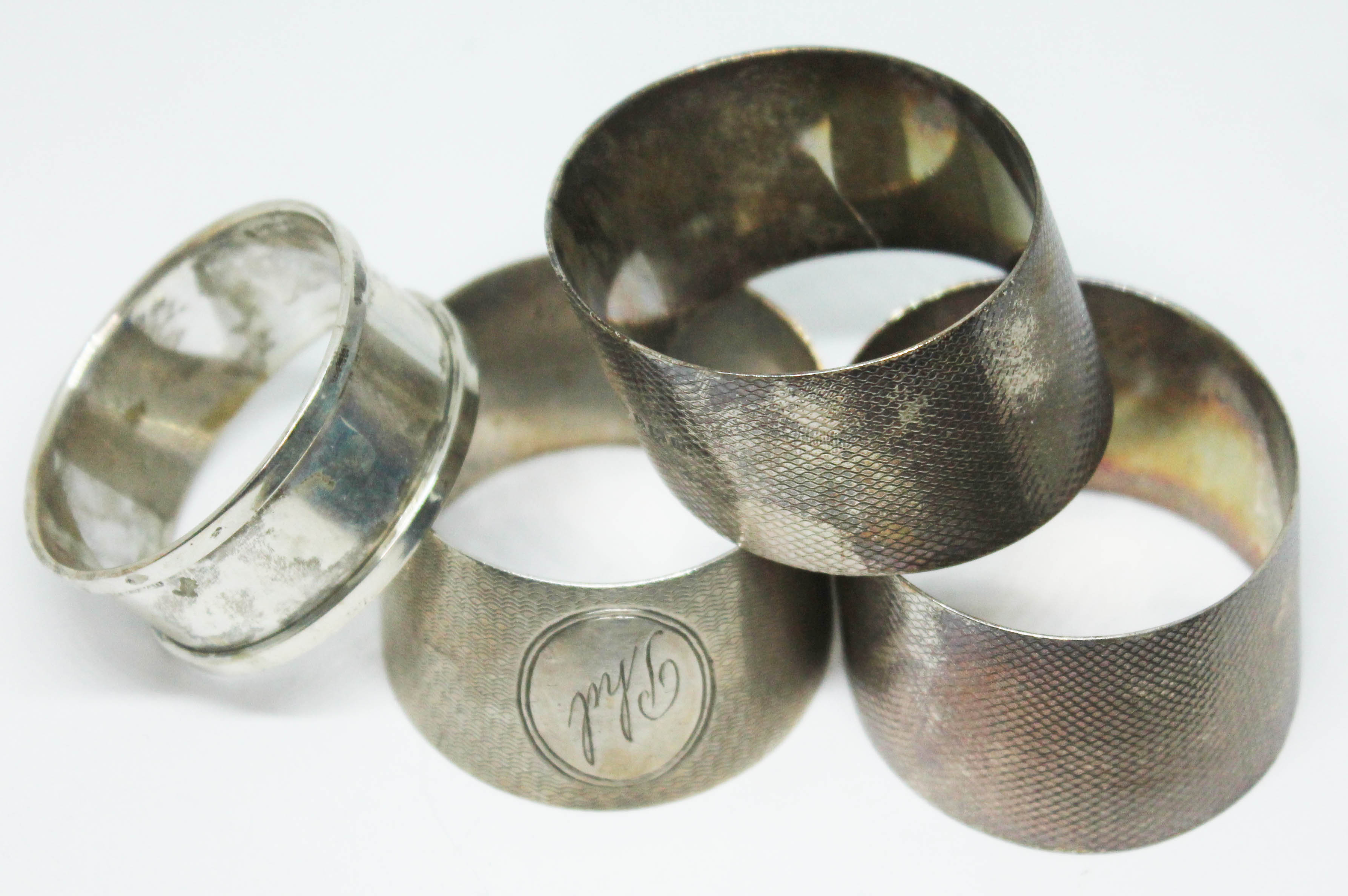 A set of three hallmarked silver serviette rings and another.