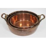 A group of three graduated copper pans with brass handles, largest diam. 42.5cm.