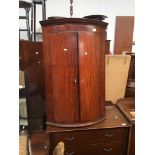 A Georgian mahogany bow front corner cupboard Catalogue only, live bidding available via our
