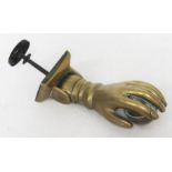 A 19th century brass door knocker formed as a hand holding a ball, length 17cm.